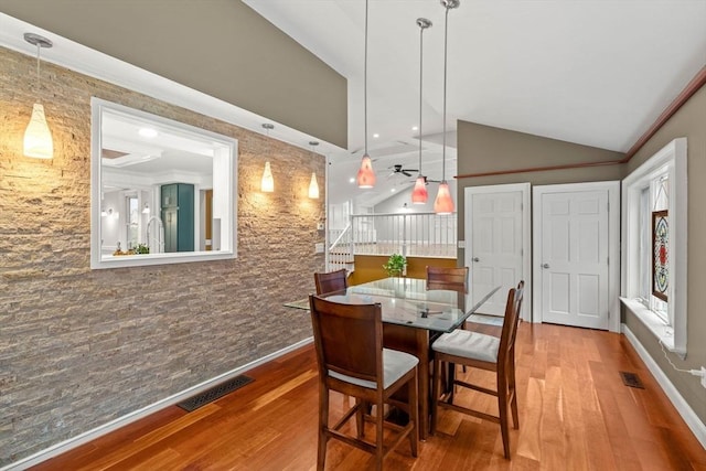 dining space with vaulted ceiling, wood finished floors, visible vents, and baseboards