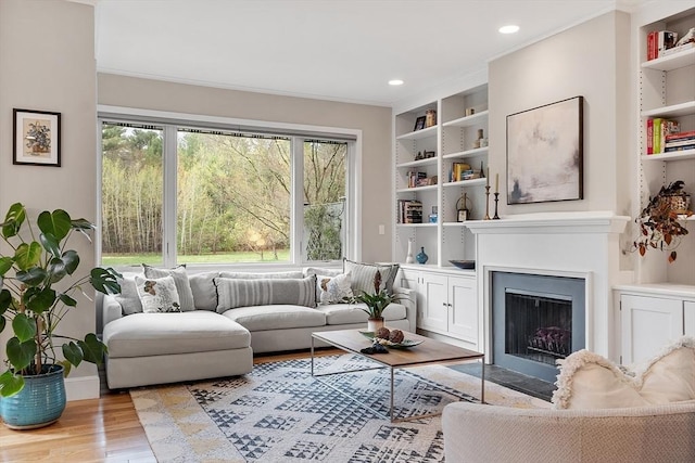 4 Greenfield Ln Unit 4, Concord, MA 01742 - living room featuring light wood-type flooring, crown molding, built in shelves, recessed lighting, and a fireplace with flush hearth