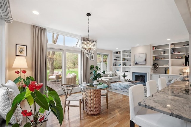 4 Greenfield Ln Unit 4, Concord, MA 01742 - dining room featuring light wood-style flooring, a chandelier, a fireplace, built in shelves, and recessed lighting