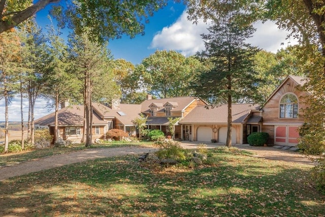 view of front facade with a chimney, driveway, an attached garage, and a front yard