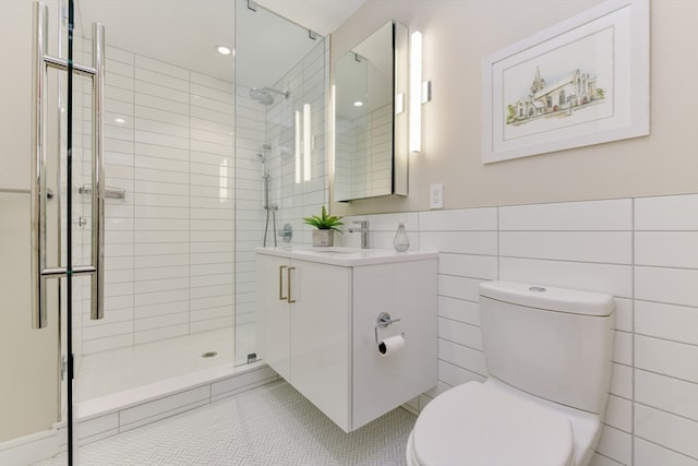 bathroom with tile walls, toilet, an enclosed shower, tile floors, and vanity