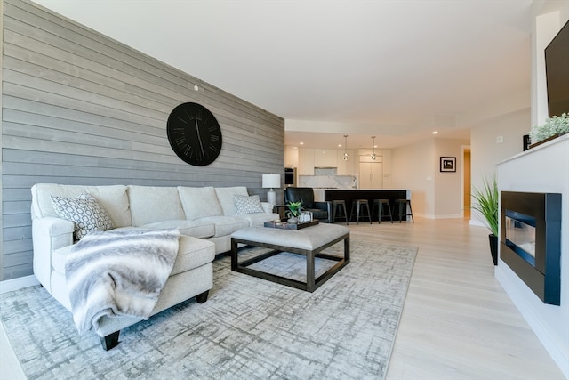 living room with light hardwood / wood-style floors and wooden walls