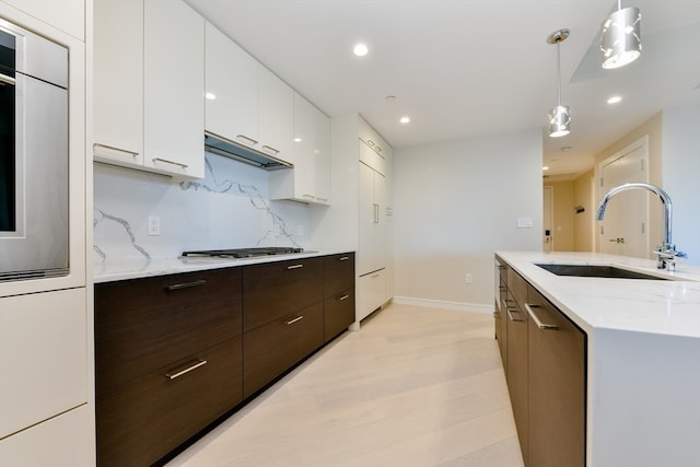 kitchen with pendant lighting, sink, white cabinets, light hardwood / wood-style flooring, and tasteful backsplash