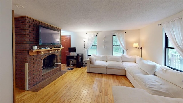 330 Arbor St, Lunenburg, MA 01462 - living room with a textured ceiling, light wood-style floors, and a brick fireplace