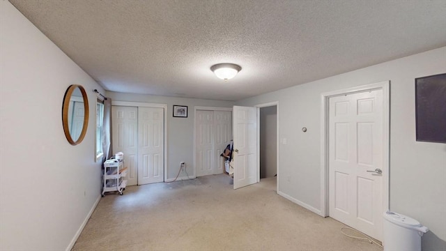 330 Arbor St, Lunenburg, MA 01462 - unfurnished bedroom featuring light carpet, two closets, and a textured ceiling