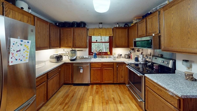 330 Arbor St, Lunenburg, MA 01462 - kitchen featuring stainless steel appliances, brown cabinets, light wood-type flooring, and light countertops