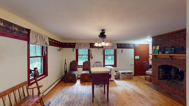 330 Arbor St, Lunenburg, MA 01462 - dining space with light wood-type flooring, a textured ceiling, baseboard heating, a chandelier, and a fireplace