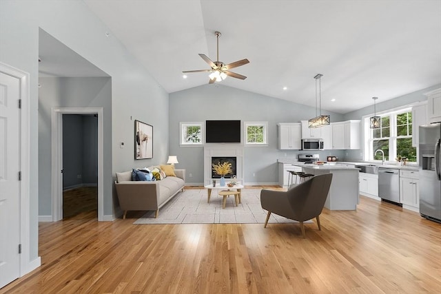 living room featuring light hardwood / wood-style flooring, plenty of natural light, high vaulted ceiling, and ceiling fan