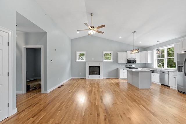 kitchen featuring white cabinetry, hanging light fixtures, plenty of natural light, stainless steel appliances, and a kitchen island