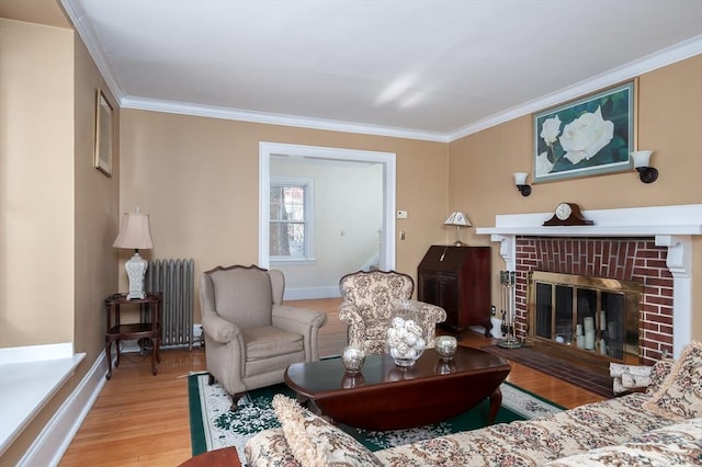 living room with a brick fireplace, radiator, crown molding, and wood finished floors