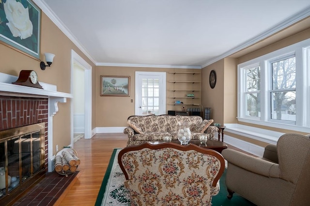 living area with baseboards, wood finished floors, a fireplace, and crown molding