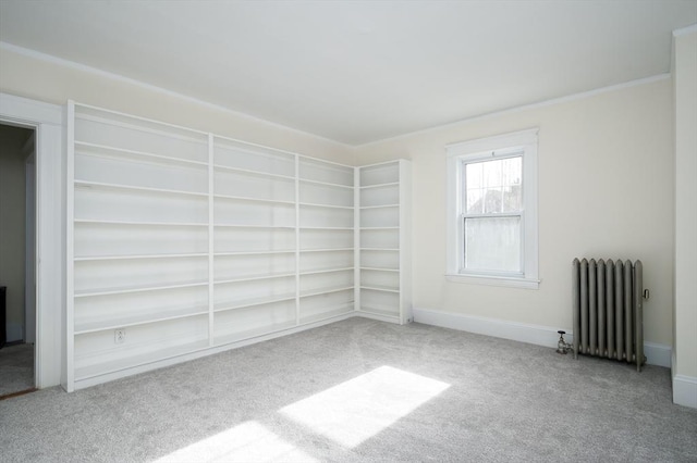 carpeted empty room featuring baseboards, radiator heating unit, and crown molding