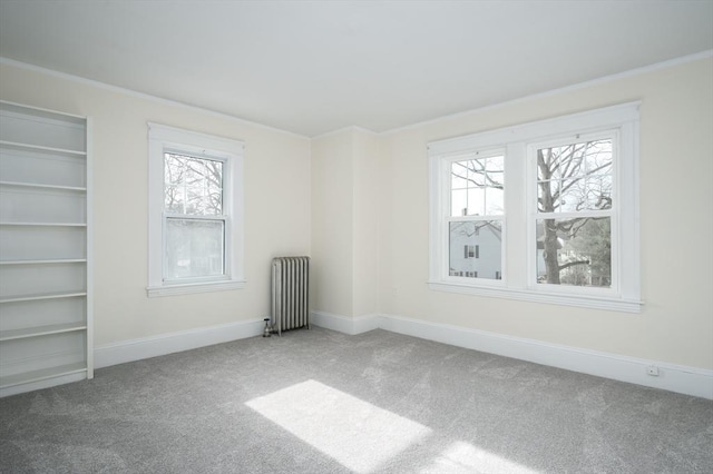 spare room with baseboards, radiator, ornamental molding, and carpet