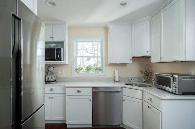 kitchen featuring a toaster, a sink, stainless steel appliances, light countertops, and white cabinets