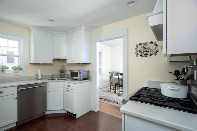 kitchen with dark wood-type flooring, dishwasher, light countertops, and white cabinetry