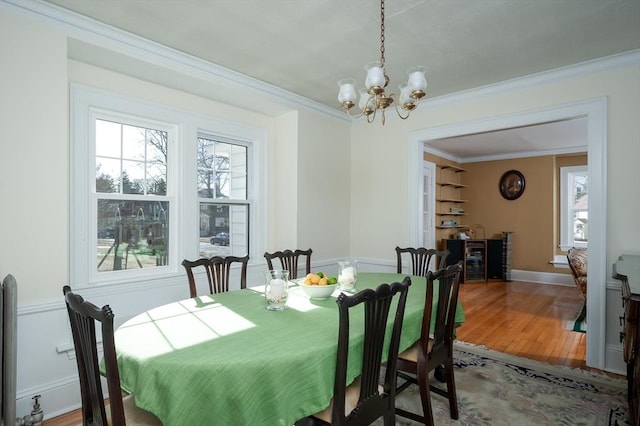 dining space featuring light wood-type flooring, baseboards, ornamental molding, and a chandelier