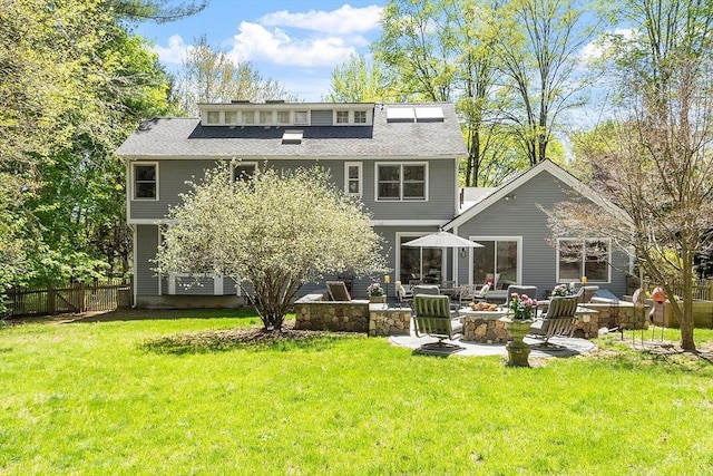 rear view of property featuring a yard, fence, a patio area, and an outdoor fire pit