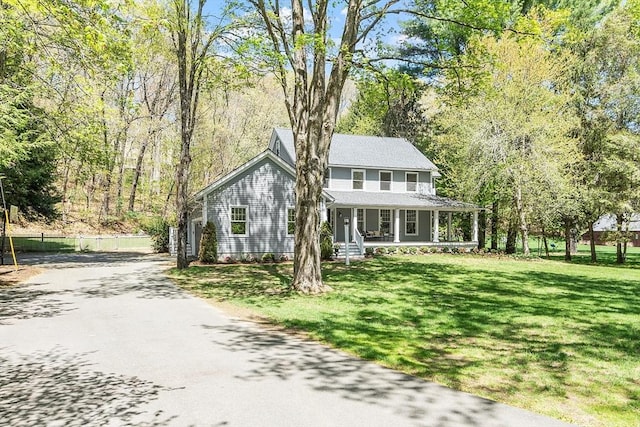 view of front of home with a front lawn, fence, covered porch, and driveway