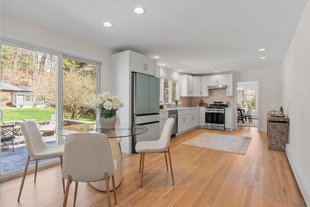 dining room with recessed lighting, light wood-type flooring, and a wealth of natural light