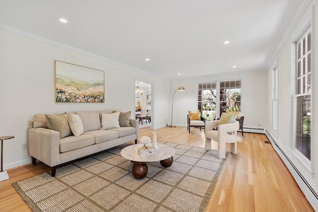 living area with a baseboard heating unit, ornamental molding, and light wood finished floors