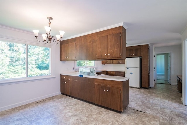 53 Iduna Ln, Amherst, MA 01002 - kitchen with freestanding refrigerator, a chandelier, light countertops, a peninsula, and ornamental molding