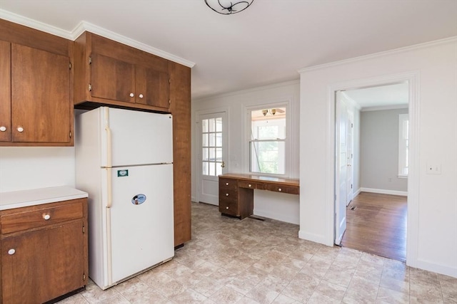 53 Iduna Ln, Amherst, MA 01002 - kitchen featuring freestanding refrigerator, ornamental molding, brown cabinetry, a desk, and light countertops