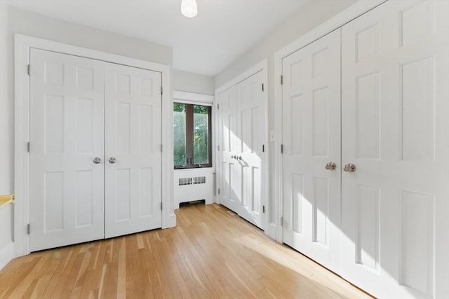 15 Park Ave, Newton, MA 02458 - unfurnished bedroom with radiator heating unit, light wood finished floors, and multiple closets