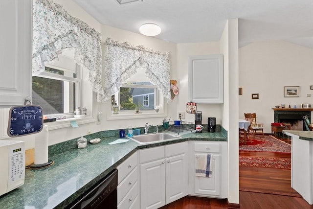 kitchen featuring dark wood-type flooring, a sink, white cabinetry, a fireplace, and white microwave