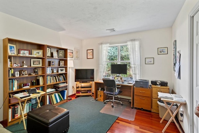 office area with wood finished floors, visible vents, and a textured ceiling