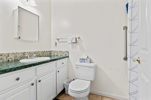 bathroom featuring tile patterned floors, toilet, tasteful backsplash, baseboards, and vanity