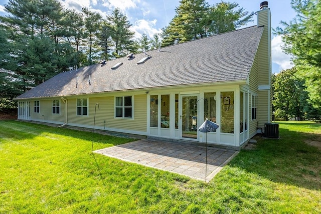 back of property featuring central AC, a yard, roof with shingles, a chimney, and a patio area