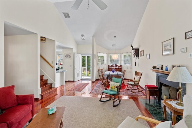 living area featuring stairway, wood finished floors, visible vents, high vaulted ceiling, and a high end fireplace