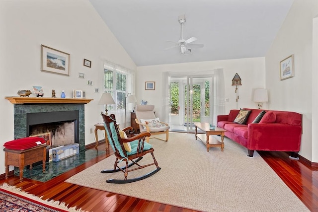 living area with a tile fireplace, high vaulted ceiling, a ceiling fan, and hardwood / wood-style floors