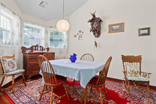 dining area featuring vaulted ceiling, visible vents, baseboards, and wood finished floors