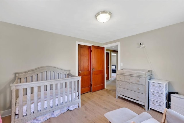 bedroom with a nursery area and light wood-type flooring