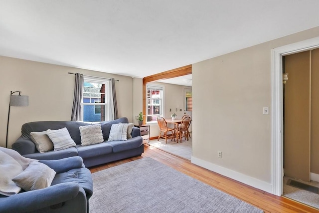 living area featuring baseboards and light wood finished floors