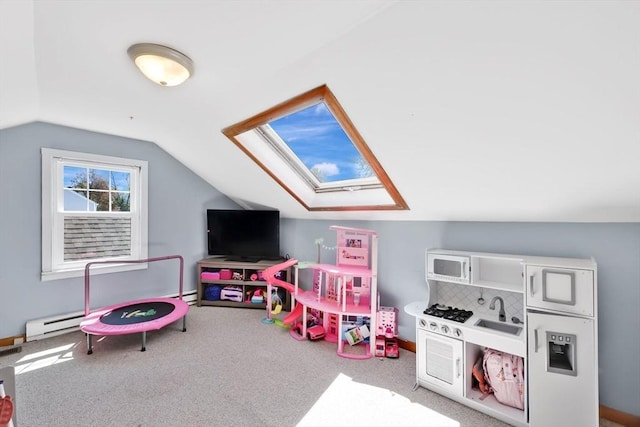 playroom featuring carpet flooring, vaulted ceiling with skylight, and baseboard heating