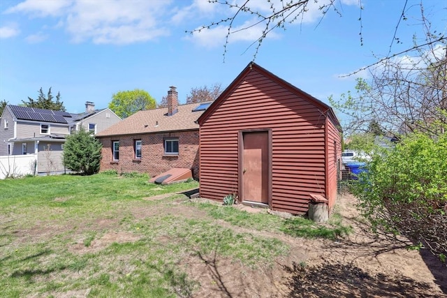 rear view of house featuring a lawn, brick siding, and a chimney