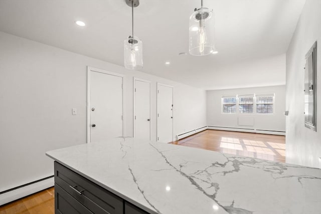 kitchen with pendant lighting, light stone countertops, light wood-type flooring, and a baseboard heating unit