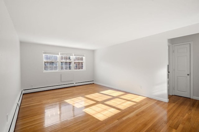 spare room with a baseboard heating unit and light hardwood / wood-style flooring