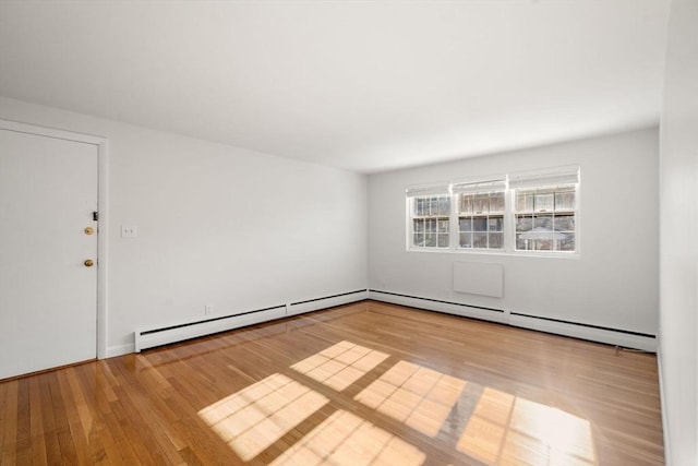 spare room with baseboard heating and light wood-type flooring