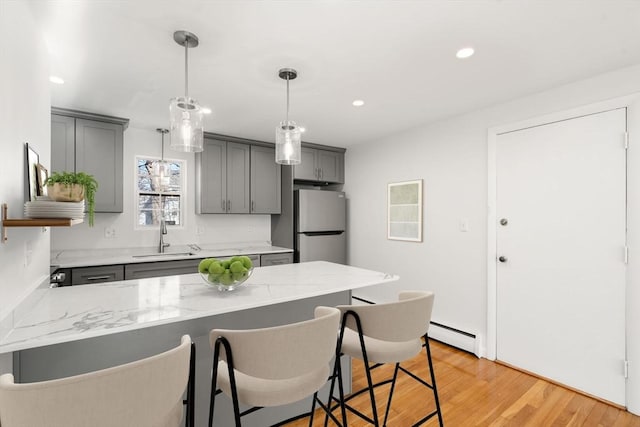 kitchen featuring pendant lighting, sink, stainless steel fridge, gray cabinets, and light hardwood / wood-style floors