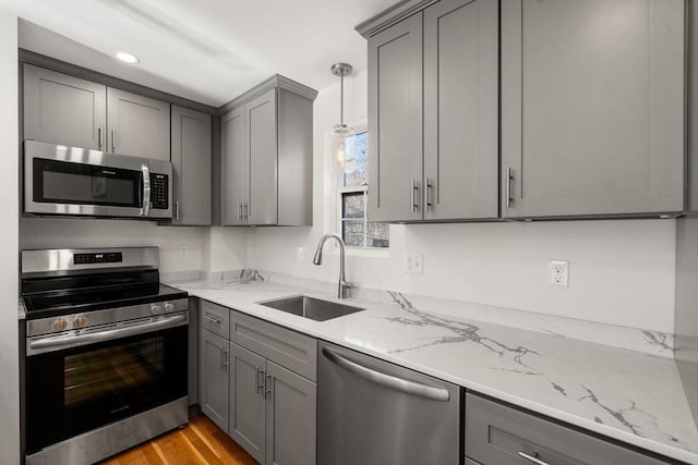 kitchen with gray cabinetry, sink, decorative light fixtures, and stainless steel appliances