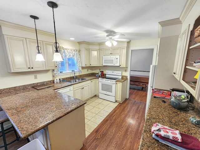 kitchen with sink, white appliances, a breakfast bar, hanging light fixtures, and kitchen peninsula