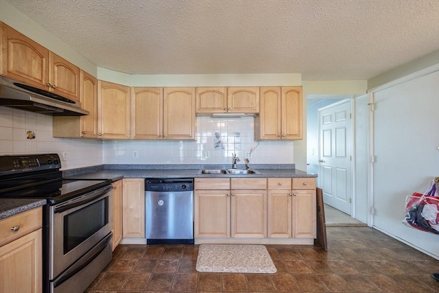 kitchen featuring a sink, light brown cabinetry, stainless steel appliances, under cabinet range hood, and dark countertops