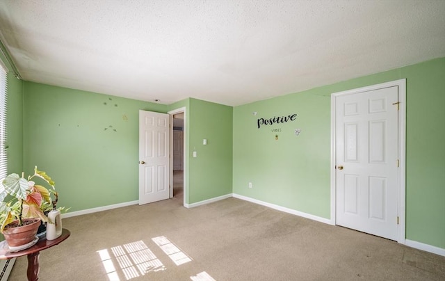 empty room featuring carpet, baseboards, and a textured ceiling