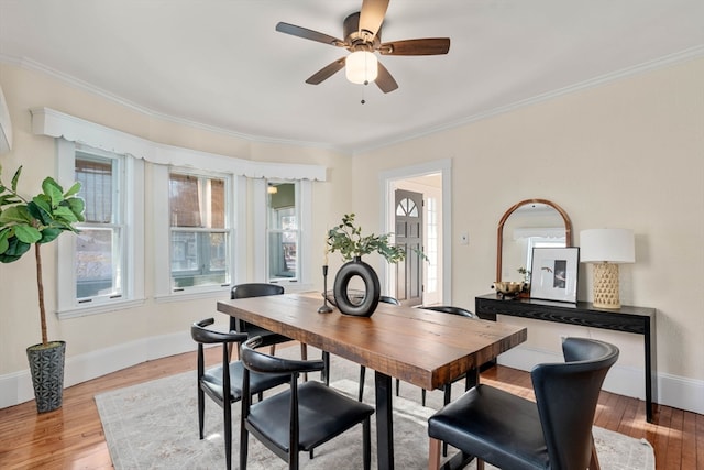 dining area with ornamental molding and light hardwood / wood-style flooring