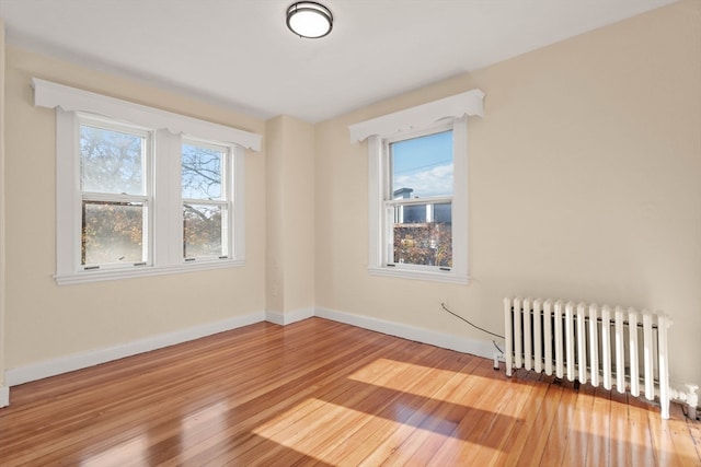 spare room featuring radiator and light hardwood / wood-style flooring