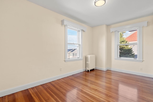 unfurnished room featuring radiator heating unit and light hardwood / wood-style flooring