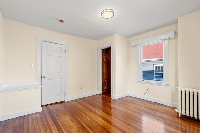 spare room featuring radiator heating unit and wood-type flooring